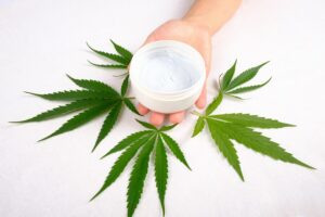 CBD Cream for Skincare with Cannabis Leaves in the Back