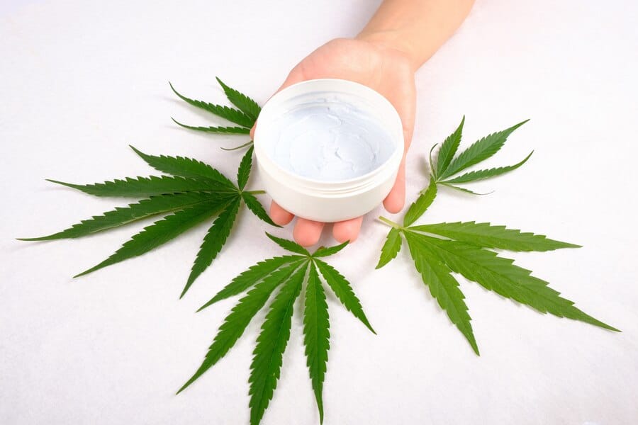CBD Cream for Skincare with Cannabis Leaves in the Back